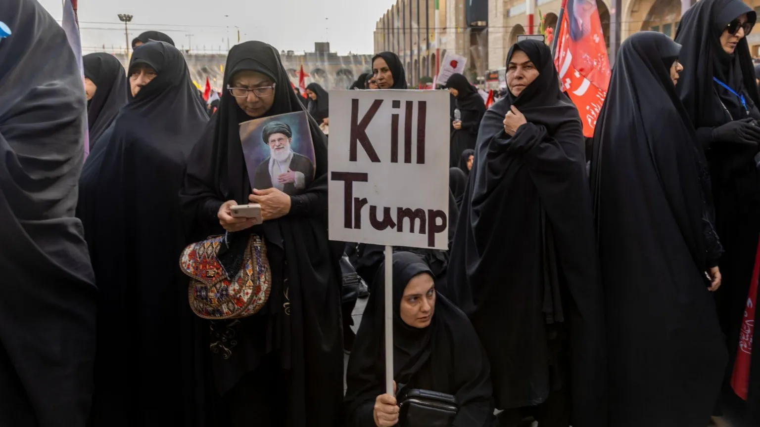 A banner depicting President Donald Trump is held aloft as mourners gather during funeral prayers held as part of the daylong funeral ceremonies for the slain Iranian Supreme Leader Ayatollah Ali Khemenei and members of his family in Tehran, Iran on July 5, 2o26