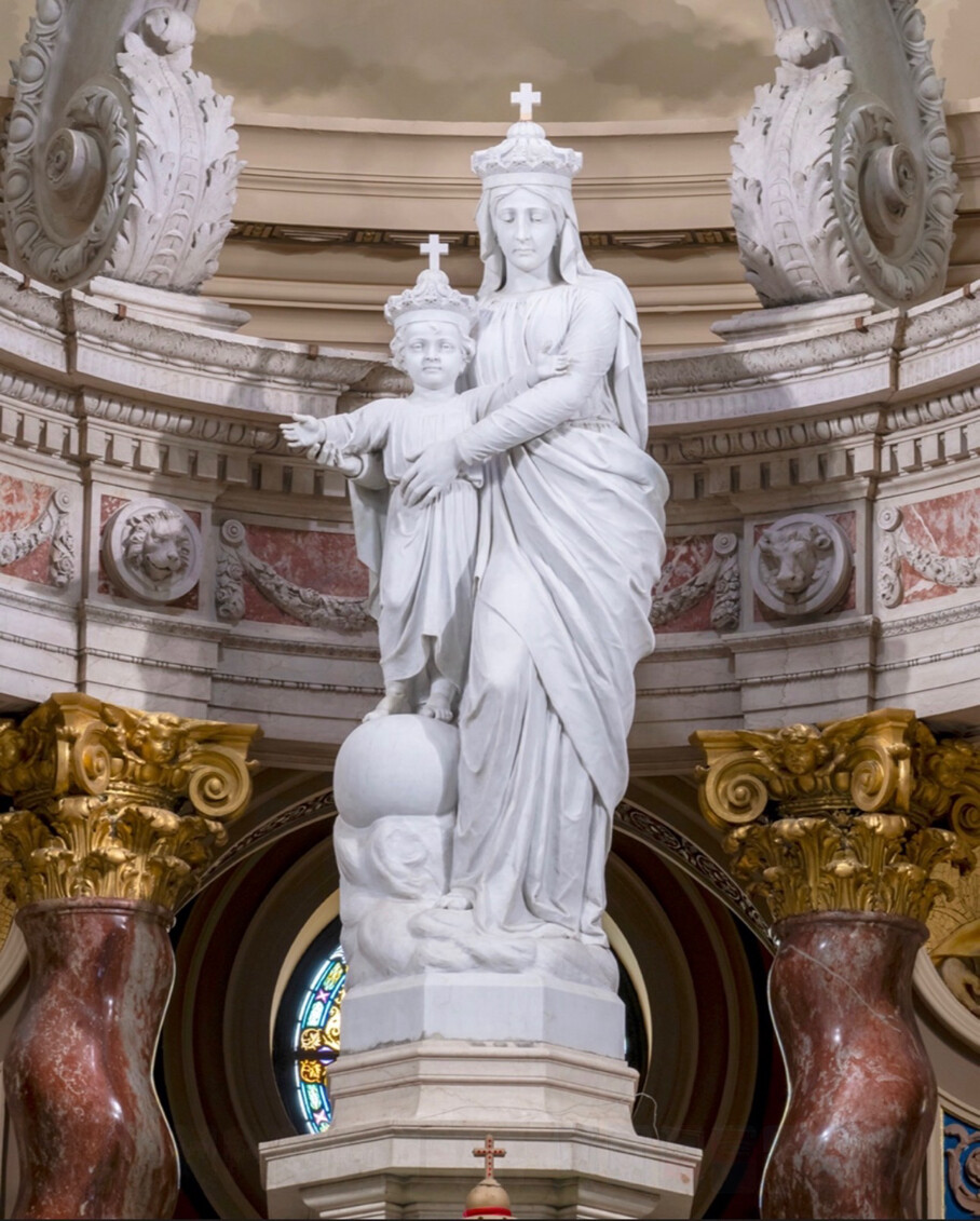 A white marble statue of the Virgin Mary holding the infant Jesus posed within an ornate church interior on 09/08/2026. The image accompanied a devotional tribute to the Virgin Mary posted by President Donald J.